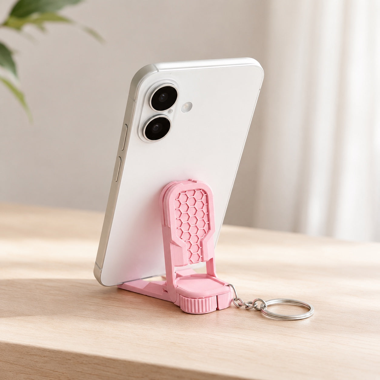 Fidget phone stand keychain holding a smartphone on a desk