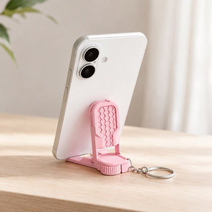 Fidget phone stand keychain holding a smartphone on a desk